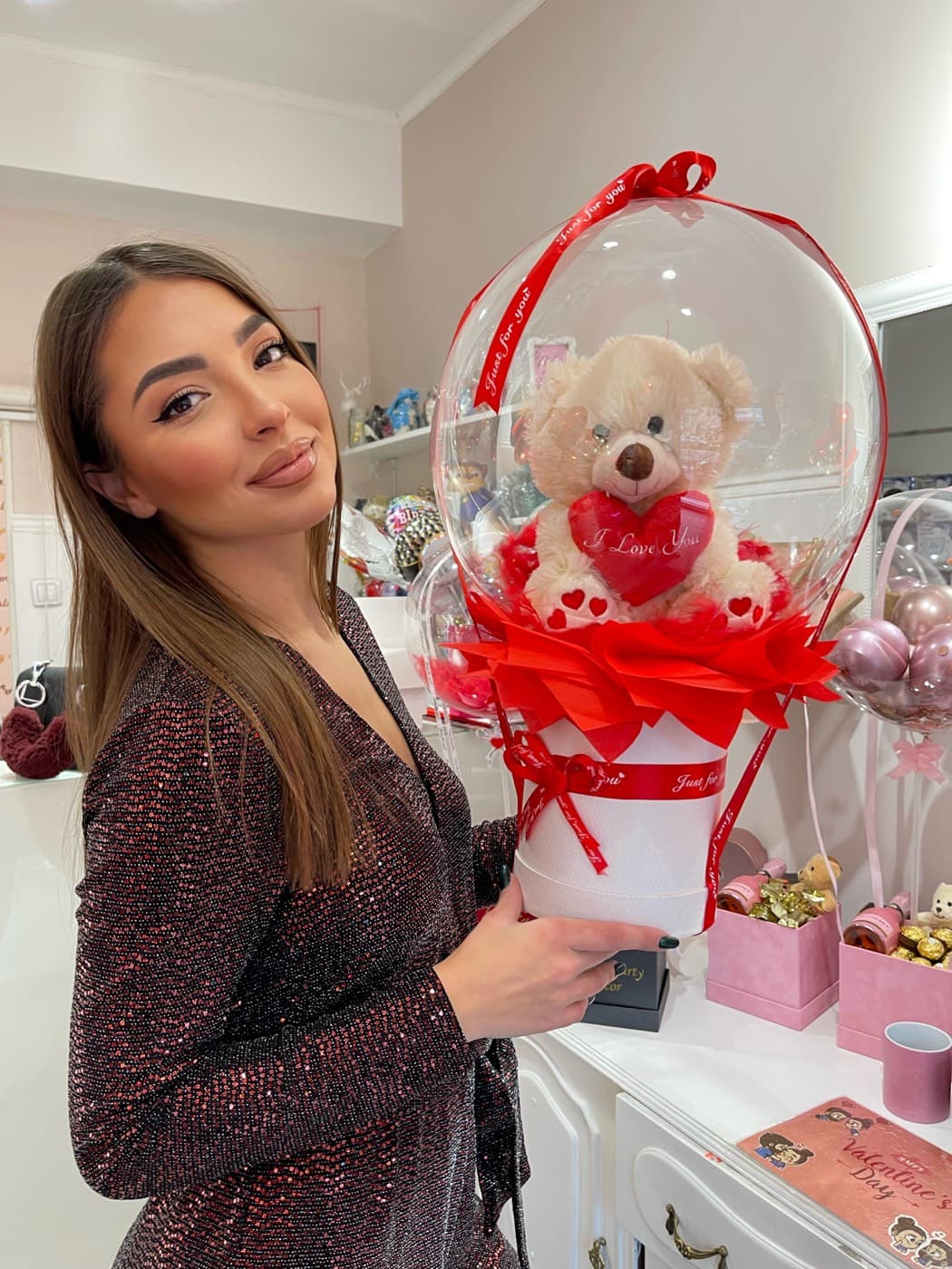 Devojka drži bubble balon sa plišanim medom i crvenim ukrasima