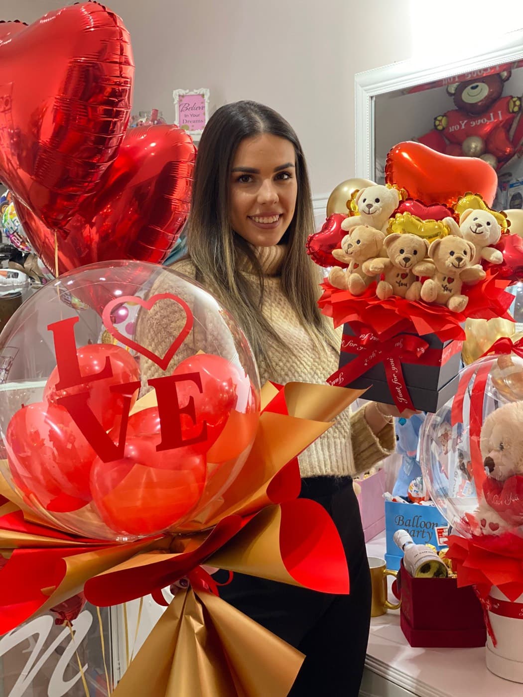 Devojka drži bubble balon buket sa crvenim srcem i pralinama