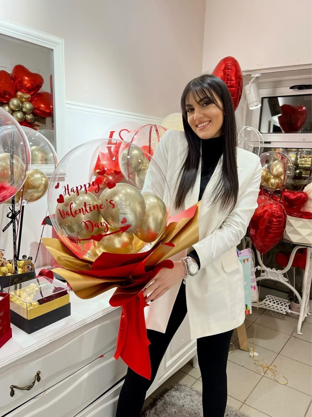 Devojka drži veliki bubble balon buket sa zlatnim balonima